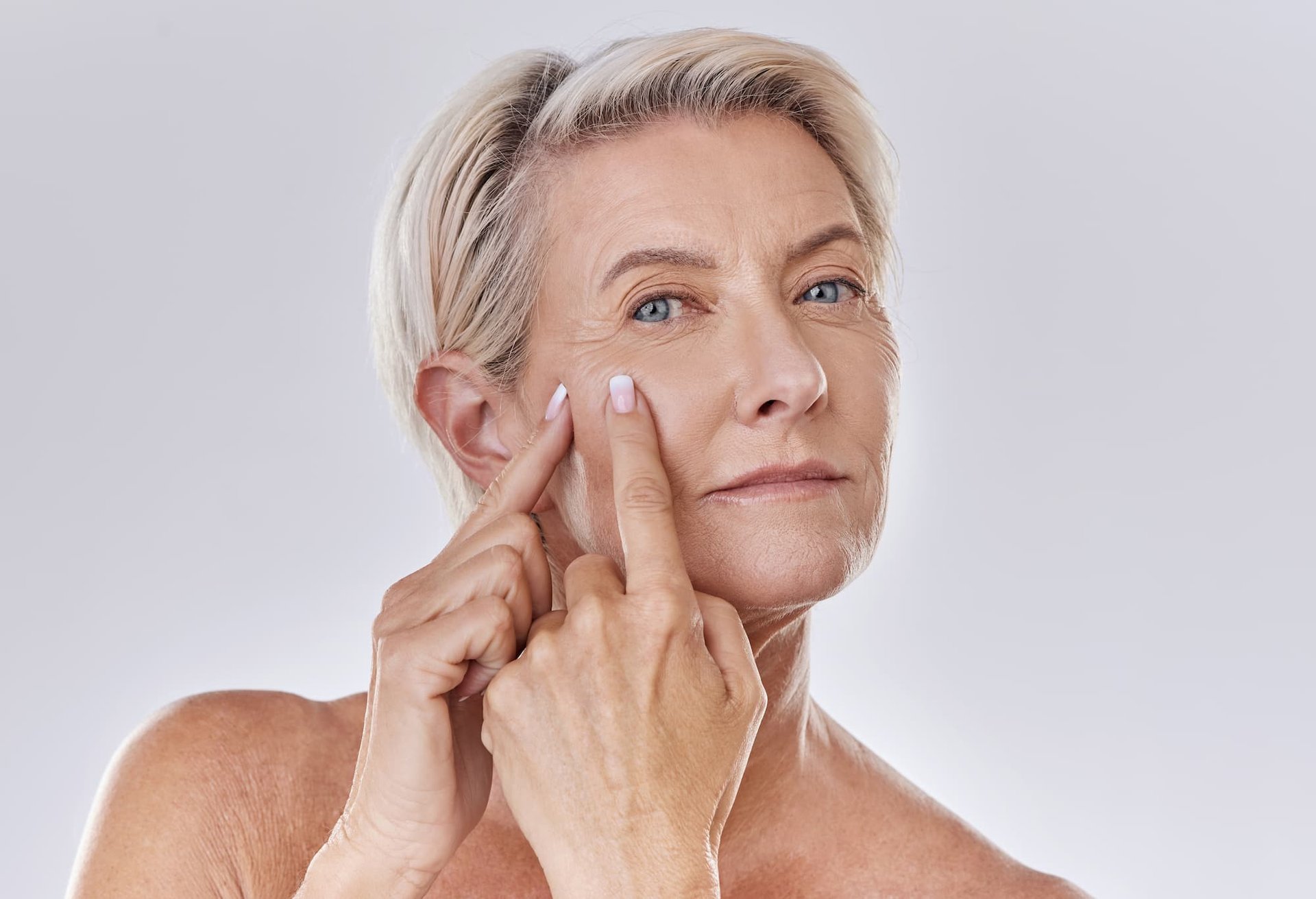 Nahaufnahme einer Frau, die sich mit ihren Fingern einen Pickel im Gesicht ausdrückt